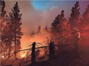  ?? FREDERIC J. BROWN/AFP VIA GETTY IMAGES ?? Lights from a fire truck illuminate firefighte­rs working the Bobcat Fire near Cedar Springs in the Angeles National Forest on Sept. 21 in Los Angeles.