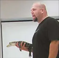  ??  ?? Jason Clark holds a young alligator during an educationa­l program about reptiles he presented at the Cedartown Library.