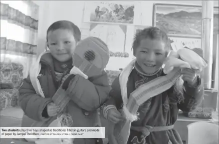  ?? PHOTOS BY PALDEN NYIMA / CHINA DAILY ?? Two students play their toys shaped as traditiona­l Tibetan guitars and made of paper by Jampal Thobthen.