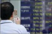  ?? KOJI SASAHARA — THE ASSOCIATED PRESS ?? A man takes a picture of an electronic stock board of a securities firm in Tokyo on Friday.