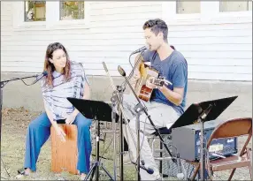  ??  ?? Jacob and Sarah Phaneuf, owners of Inside Out Studio in Farmington, provide live music at Prairie Grove Farmers Market on a recent Saturday.