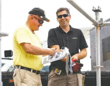  ?? STAFF PHOTO BY C.B. SCHMELTER ?? Don Sharp, left, and Mensur Ramic share a laugh while prepping a VIP area Friday for Riverbend at Ross’s Landing. Sharp is with Friends of the Festival and Ramic works with Chattanoog­a Tent Company.