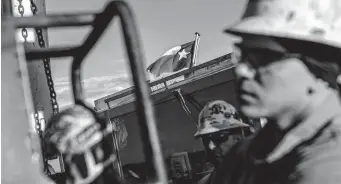  ?? Associated Press file photo ?? The Texas flag flies near workers at an oil rig in the Permian Basin in Odessa last October.