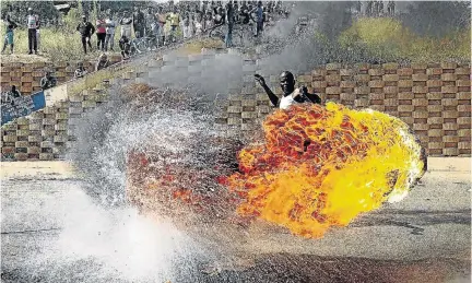  ?? /THULANI MBELE ?? A protester swirls around a burning tyre during one of service delivery protests. The writer says political parties will need to convince voters next year on how they will turn things around.