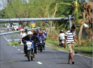  ?? CHARISM SAYAT/AFP ?? Motorists drive past downed electric posts on the national road after typhoon Nock-Ten made landfall in Nabua, Camarines Sur, the Philippine­s, yesterday.