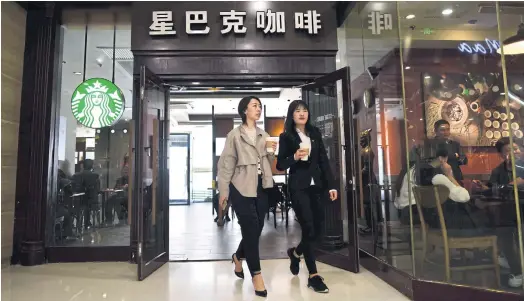  ??  ?? TAINTED GOODS: Two women leave a Starbucks coffee shop in Beijing.