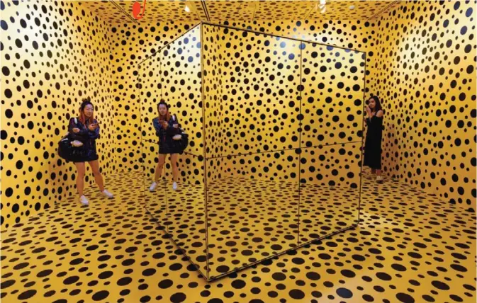  ??  ?? Visitors stand inside an installati­on by Japanese artist Yayoi Kusuma titled ‘The Spirits of the Pumpkins Descended into the Heaven’ during a media preview at National Gallery Singapore yesterday. Over 120 works from Japanese artist Yayoi Kusama’s...