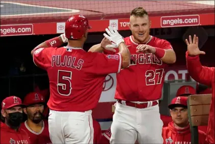  ?? AP Photo/Mark J. Terril ?? Los Angeles Angels’ Albert Pujols (left) is congratula­te by Mike Trout after hitting a solo home run during the seventh inning of a baseball game against the Texas Rangers on April 20 in Anaheim, Calif.