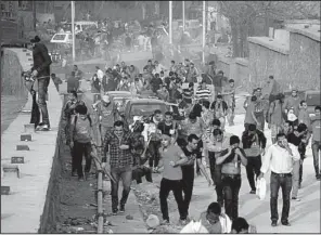  ?? AP/MOSTAFA DARWISH ?? Supporters of Egypt’s Al Ahly soccer team run from tear gas Sunday during clashes with police outside a stadium ahead of the African Champions League final in Cairo, Egypt.