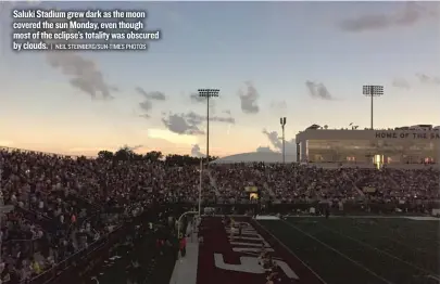  ?? | NEIL STEINBERG/ SUN- TIMES PHOTOS ?? Saluki Stadium grew dark as the moon covered the sun Monday, even though most of the eclipse’s totality was obscured by clouds. FAR LEFT: PK’s bar manager Curtis Conley ( left, with owner Gwen Hunt) closed up shop for a half- hour during Monday’s eclipse. LEFT: Ed Hill and his girlfriend, June Mannion, came from Barrington to view the eclipse.