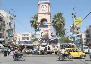  ?? — Reuters ?? People ride on their motorbikes along a street at the clock square in the city of Idlib.