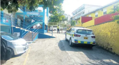  ?? PHOTO BY HOPETON BUCKNOR ?? A guard keeps watch on the compound of Cornwall College where the dean of discipline was assaulted by a parent and others yesterday morning.