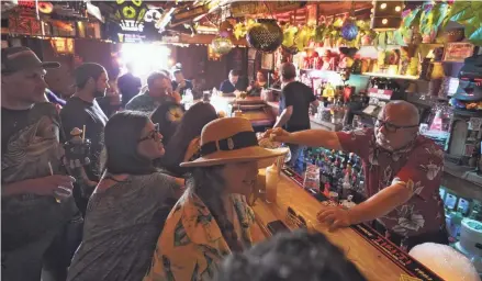  ??  ?? Patrons enjoy cold tropical cocktails July 7 in the Tiki-Ti bar as it reopens on Sunset Boulevard in Los Angeles, where county public health officials have urged people to resume wearing masks indoors regardless of their vaccinatio­n status.