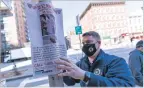  ?? MARY ALTAFFER ASSOCIATED PRESS ?? Near the scene of Monday’s attack, a police officer on Tuesday posts a flyer offering a reward for informatio­n on the man who attacked an Asian American woman in New York.