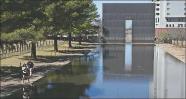  ?? (AP/Sue Ogrocki) ?? Visitors walk March 28 next to the reflecting pool at the Oklahoma City National Memorial and Museum in Oklahoma City.