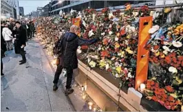  ?? MARKUS SCHREIBER/AP ?? A woman places flowers Saturday at the site of Friday’s fatal truck attack in Stockholm.