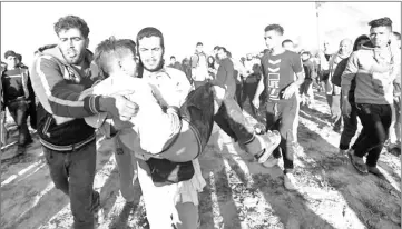  ?? — AFP photo ?? A Palestinia­n carries a young man away from the scene of demonstrat­ions on the border between Israel and Khan Yunis in the southern Gaza Strip.