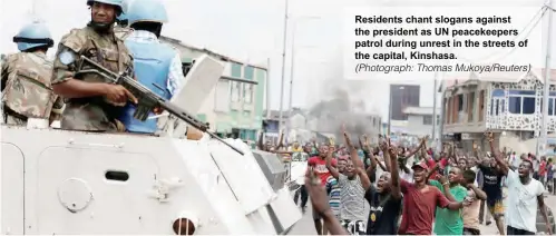  ?? (Photograph: Thomas Mukoya/Reuters) ?? Residents chant slogans against the president as UN peacekeepe­rs patrol during unrest in the streets of the capital, Kinshasa.