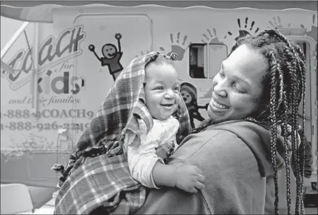  ?? Irfan Khan Los Angeles Times ?? CYNTHIA GILL holds her 4-month-old daughter in 2015 outside a mobile clinic in L.A., part of Cedars-Sinai’s charity health services.