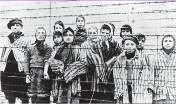  ??  ?? Children stand behind barbed wire fencing at Auschwitz concentrat­ion camp in Poland in January 1945.