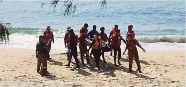  ??  ?? PASUKAN penyelamat mengangkat mayat Khairul yang ditemui terdampar di persisiran pantai.