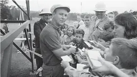  ?? THE ASSOCIATED PRESS ?? Arnold Palmer signs autographs after a practice round for the 1964 Masters. His signature, with every letter legible, was one of the most famous in sports.