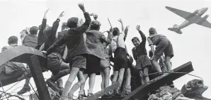  ??  ?? Our heroes: Berlin children cheer as a U.S. plane flies in supplies