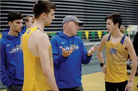  ?? Photo courtesy of JBU Sports Informatio­n ?? John Brown junior Eathan Devine (from left), senior Nate Wertjes, head coach Scott Schochler and freshman Jadin Whiting have a post-race discussion after the distance medley relay at the Missouri Southern State Lion Invite held in early February in Joplin, Mo. The entire outdoor track and field season for JBU was canceled because of the covid-19 pandemic.