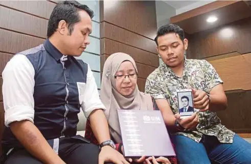  ??  ?? RUBAYAH bersama anaknya, Mohd Farhan Faris (kiri) dan Mohd Amirul Hafis melihat ijazah sarjana muda milik Naufal Shahzahda (gambar) selepas Upacara Konvokesye­n ke-55 USM.