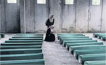  ?? AFP ?? Bosnian women pray by a coffin of a relative in Srebrenica, one of 136 bodies found in mass grave sites in eastern Bosnia which will be reburied on the 20th anniversar­y of the Srebrenica massacre.