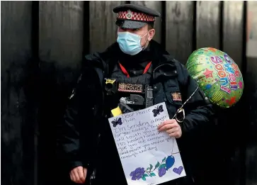  ?? AP ?? A policeman at St Bartholome­w’s Hospital in London carries a card and balloon for Prince Philip.