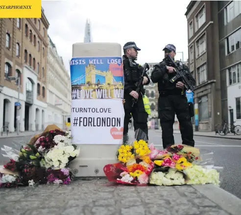  ?? CHRISTOPHE­R FURLONG / GETTY IMAGES ?? Armed police stand guard in front of floral tributes on Southwark Street near the scene of Saturday’s terrorist attack in London, England. Among the seven people killed was a young Canadian from British Columbia who moved to Europe to be with her...