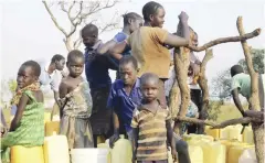  ??  ?? BIDI BIDI, Uganda: In this Dec 10, 2016 photo, a group of children and adults gather around a bore-hole in the Bidi bidi refugee settlement.