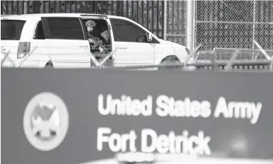  ?? GRAHAM CULLEN/THE FREDERICK NEWS-POST ?? A member of the Frederick Police Department Special Response Team peers out of a minivan before the team entered Fort Detrick in a convoy following a shooting in the Riverside Tech Park on Tuesday in Frederick, Md.