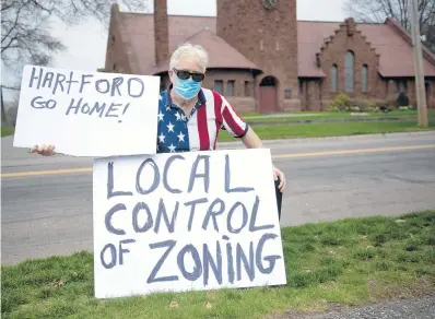  ?? KASSI JACKSON PHOTOS/HARTFORD COURANT ?? Dana Benson, 64, of Easton, poses with his signs Saturday as community members of Fairfield County protested against proposed zoning legislatio­n they say removes local decision-making.