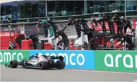  ??  ?? Mercedes’ Lewis Hamilton crosses the finish line as his team celebrate at the side of the track. Photograph: Matthias Schräder/Reuters