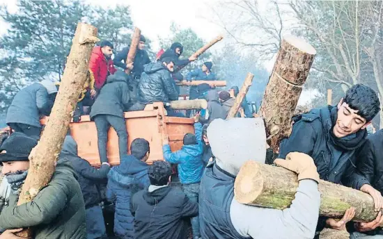  ?? LEONID SHCHEGLOV / AFP ?? Migrants descarrega­nt troncs proporcion­ats per les autoritats bielorusse­s