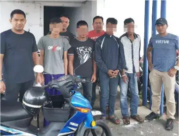  ??  ?? The suspects (from front second left) and police with one of the seized motorcycle­s.