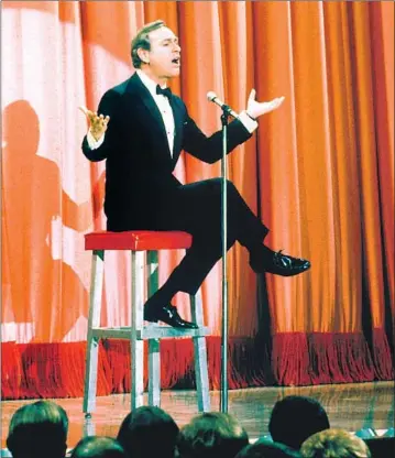  ?? Martin Mills Getty Images ?? SHELLEY BERMAN performed his comedy routines, such as this one circa 1970, sitting on a custom stool.