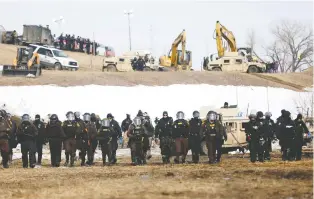  ?? TERRAY SYLVESTER/REUTERS ?? A judge's decision to allow the Dakota Access oil pipeline to run until April 19 was decried as violating the rights of Native Americans. Officers gather at a protest near Cannon Ball, N.D., in 2017.