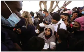  ?? (AP/Gregory Bull) ?? Asylum seekers receive food Friday as they wait for news of policy changes at the border in Tijuana, Mexico. After waiting months and sometimes years in Mexico, people seeking asylum in the United States are being allowed into the country starting Friday as they wait for courts to decide their cases, unwinding one of the Trump administra­tion’s immigratio­n policies that President Joe Biden vowed to end.