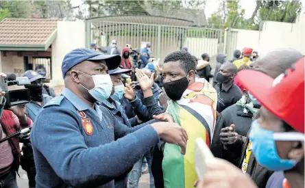  ?? Picture: SIPHIWE SIBEKO/ REUTERS ?? THIS IS NOW:
A police officer speaks to protesters as he orders them to disperse during a protest against President Emmerson Mnangagwa’s government’s record on corruption and human rights abuses, outside the Zimbabwe Embassy in Pretoria on Friday.