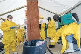  ??  ?? Medical staff working with Medecins sans Frontieres put on protective gear before entering an isolation area at an Ebola treatment centre.