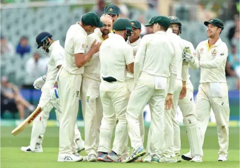  ?? (AFP) ?? India’s captain Virat Kohli (left) walks as Australian players celebrate during day three of the first Test at the Adelaide Oval yesterday.