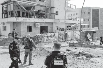  ?? JALAA MAREY TNS ?? Israeli forces check a building that was hit by a Hezbollah rocket in Kiryat Shmona in northern Israel near the Lebanon border, on Wednesday. A civilian was killed in northern Israel, medics say, after Lebanon’s Hezbollah launched a barrage of rockets into Israel in retaliatio­n for an overnight strike that killed ‘seven rescuers.’