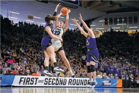  ?? AP PHOTO/MATTHEW PUTNEY ?? Iowa guard Caitlin Clark drives to the basket as she is double-teamed by Holy Cross guards Kaitlyn Flanagan, left, and Bronagh Power-Cassidy in the second half of an NCAA tournament first-round game Saturday in Iowa City. Clarked helped the host Hawkeyes, a No. 1 seed, win 91-65.
