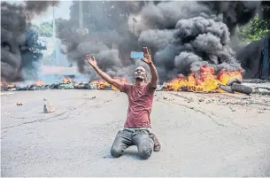  ?? RICHARD PIERRIN AFP VIA GETTY IMAGES ?? A man films himself in front of tires on fire during a general strike launched by several profession­al associatio­ns and companies to denounce insecurity in Port-au-Prince on Monday.