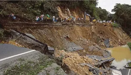  ?? REUTERS PIC ?? People walking in an area of a highway collapsed by Hurricane Nate in Casa Mata, Costa Rica, on Friday.