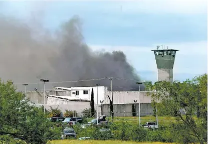  ??  ?? Los rebeldes quemaron cajas para bloquear los accesos al penal, lo que generó una cortina de humo.