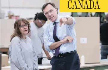  ?? PAUL CHIASSON / THE CANADIAN PRESS ?? Finance Minister Bill Morneau visits with a worker at a kitchen counter factory in Montreal on Tuesday.